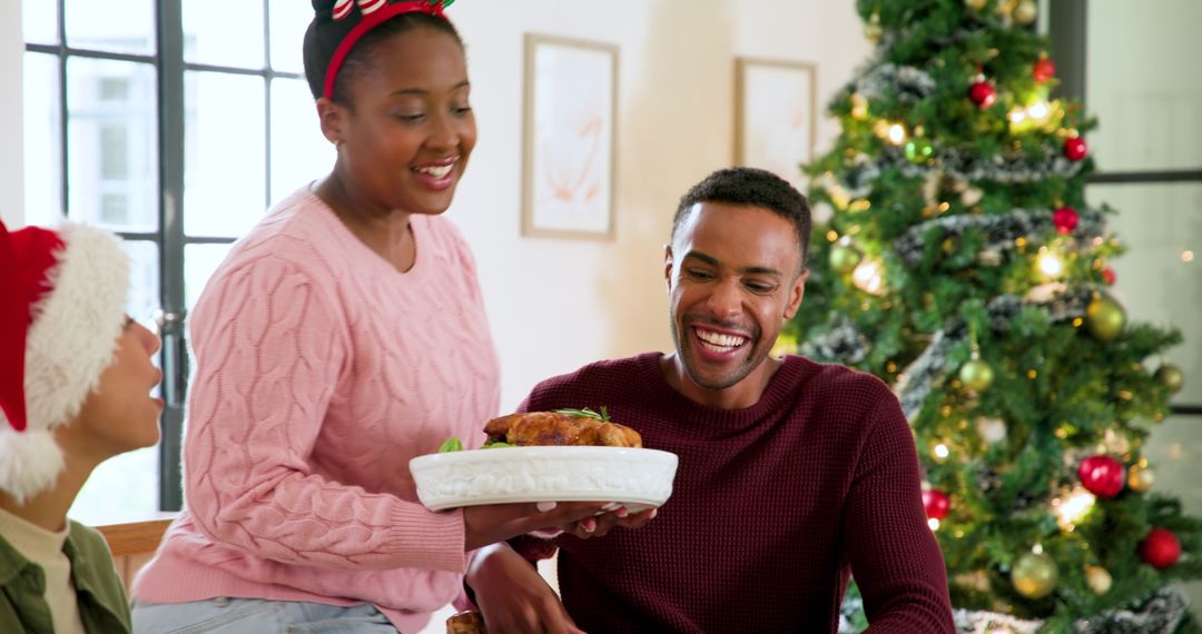 Family Celebrating Christmas with Roasted Chicken by Christmas Tree