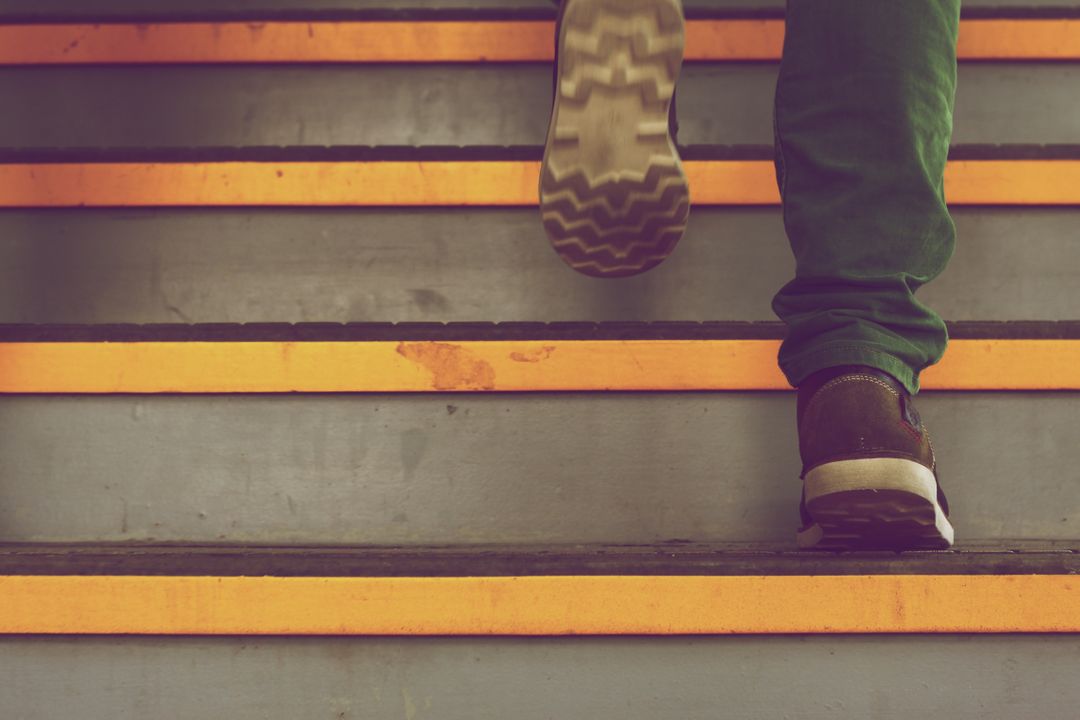 Close Up of Person Climbing Staircase with Yellow Stripes - Free Images, Stock Photos and Pictures on Pikwizard.com