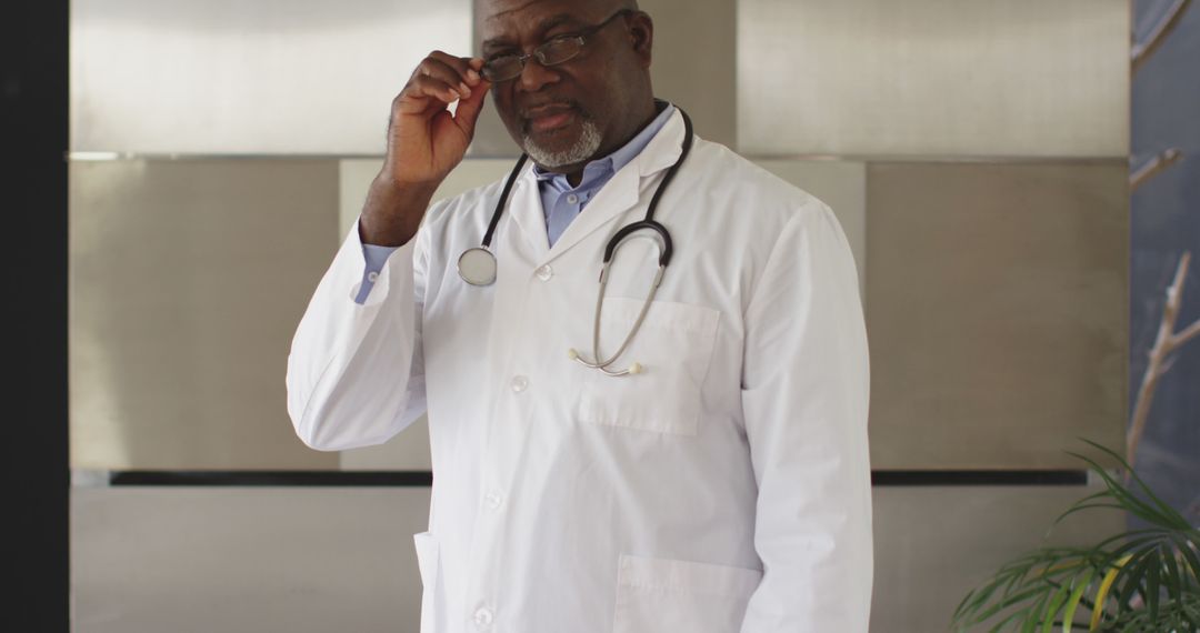 Confident African American Male Doctor Adjusting Glasses in Hospital - Free Images, Stock Photos and Pictures on Pikwizard.com