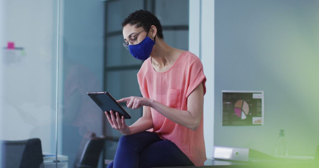 Businesswoman Working on Tablet Wearing Face Mask in Modern Office - Free Images, Stock Photos and Pictures on Pikwizard.com