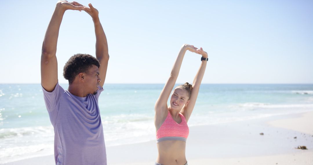 Diverse Duo Enjoys Stretching on Sunny Beach