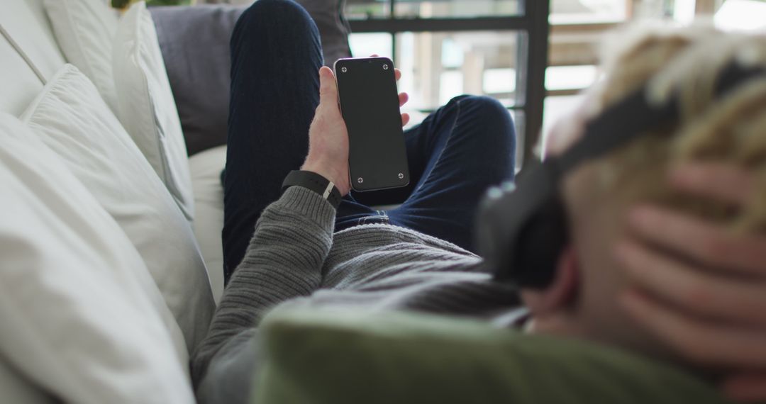 Man Relaxing on Couch Using Smartphone with Headphones - Free Images, Stock Photos and Pictures on Pikwizard.com