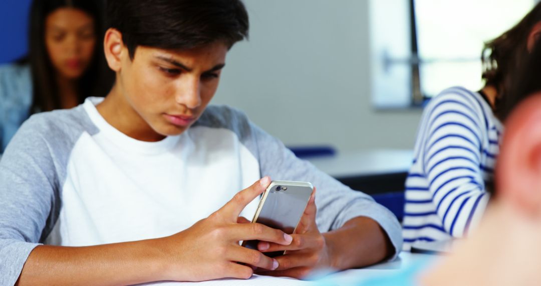 Teenager Concentrating on Smartphone in Classroom - Free Images, Stock Photos and Pictures on Pikwizard.com