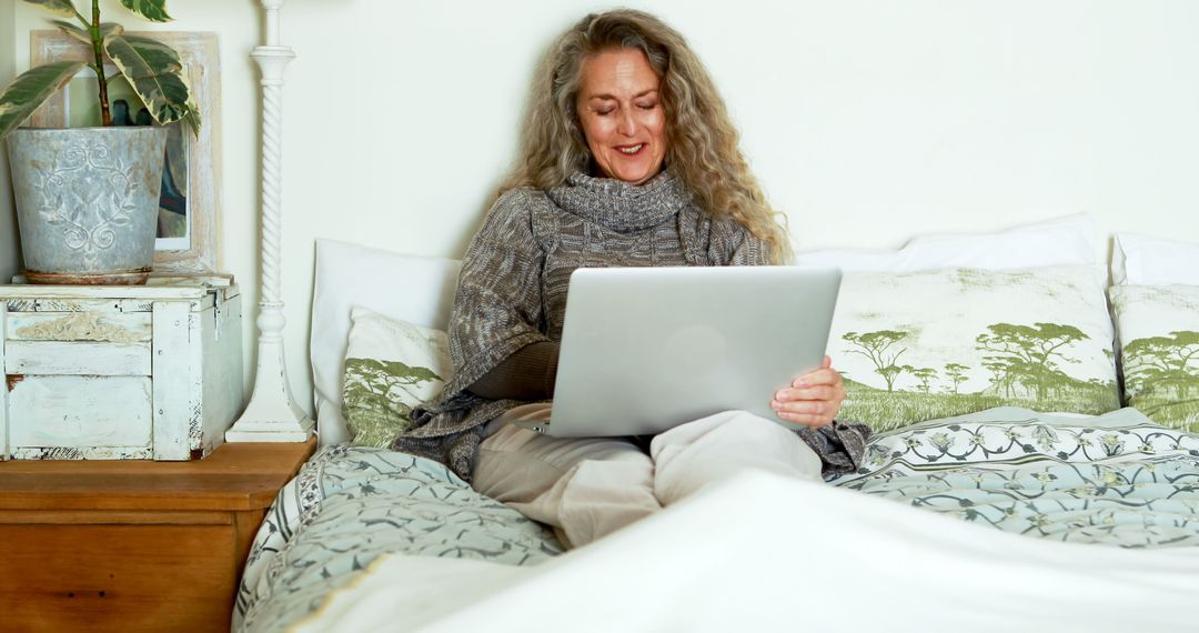 Senior Woman Sitting in Bed Using Laptop with Smile - Free Images, Stock Photos and Pictures on Pikwizard.com