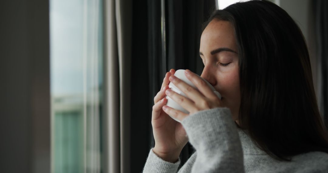 Young Woman Enjoying Hot Beverage By Window - Free Images, Stock Photos and Pictures on Pikwizard.com