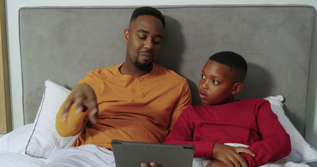 Father and Son Relax with Tablet Technology in Cozy Bedroom Setting