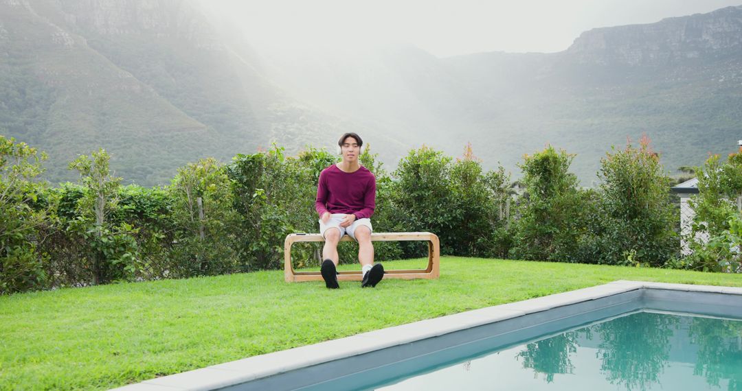 Man Relaxing on Bench Near Pool with Scenic Mountain View