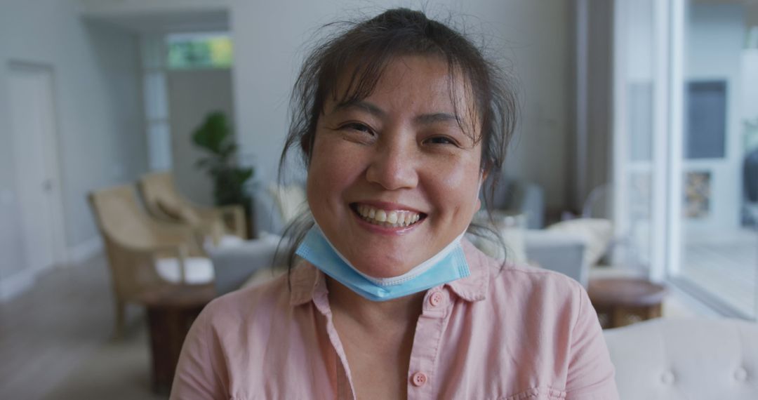 Smiling Woman Relaxing Indoors with Mask Around Neck