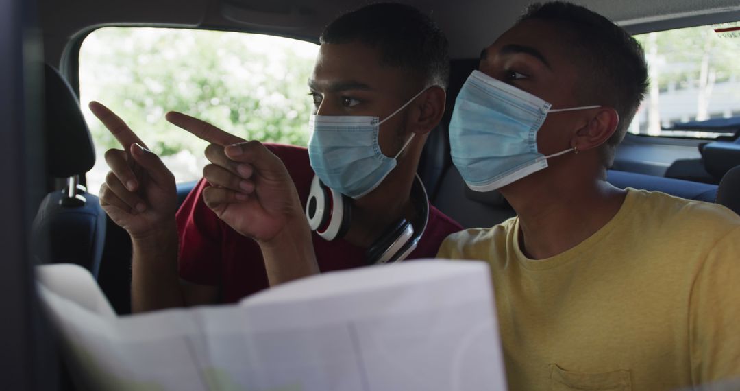 Two Friends with Masks Navigating Travel with Map in Cab