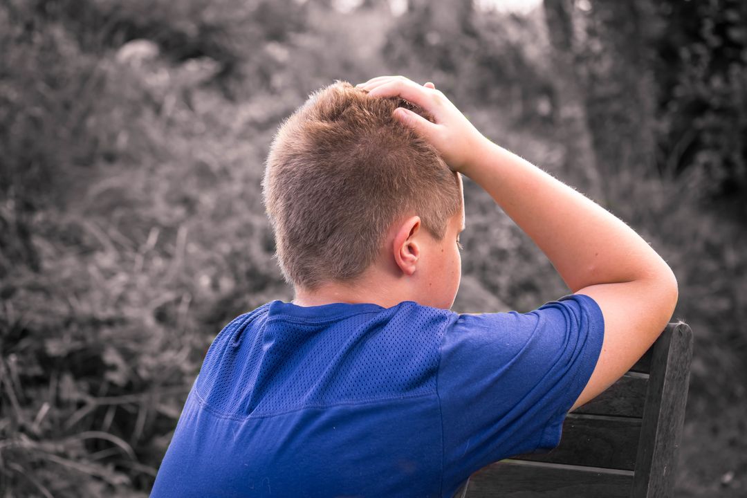 Sad boy sitting alone in nature holding head with hand - Free Images, Stock Photos and Pictures on Pikwizard.com