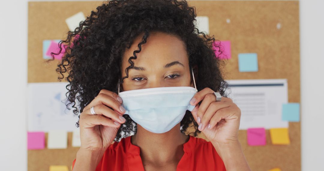 Woman Adjusting Surgical Face Mask in Office Environment - Free Images, Stock Photos and Pictures on Pikwizard.com