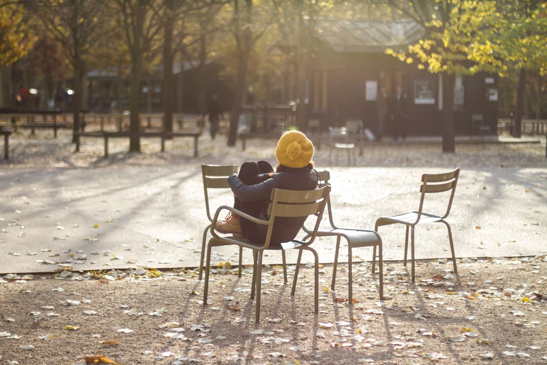 Person Relaxing on a Park Bench in Autumn Sunlight - Free Images, Stock Photos and Pictures on Pikwizard.com