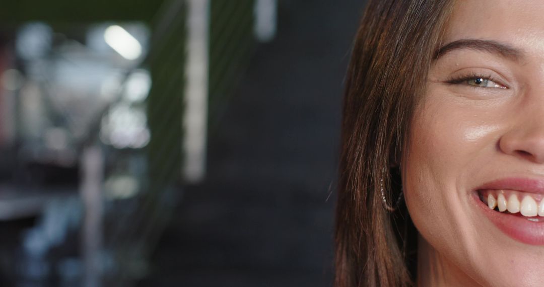 Smiling Indian woman showing teeth and hoop earring on diagonal staircase with bokeh