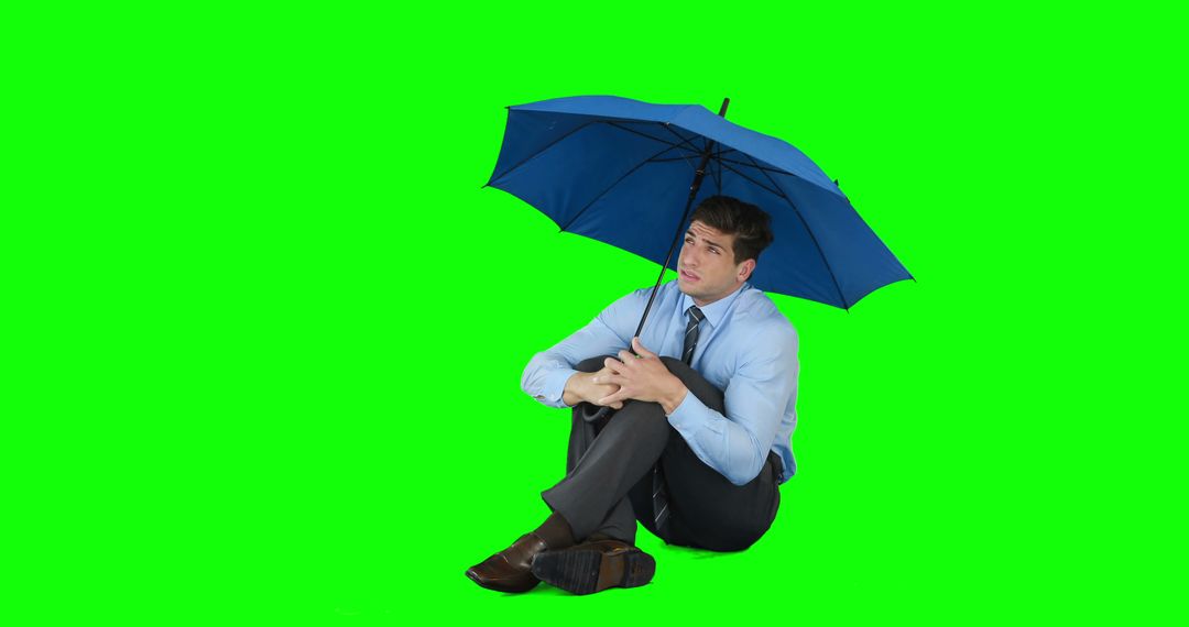 Young businessman sheltering with umbrella on green screen - Free Images, Stock Photos and Pictures on Pikwizard.com