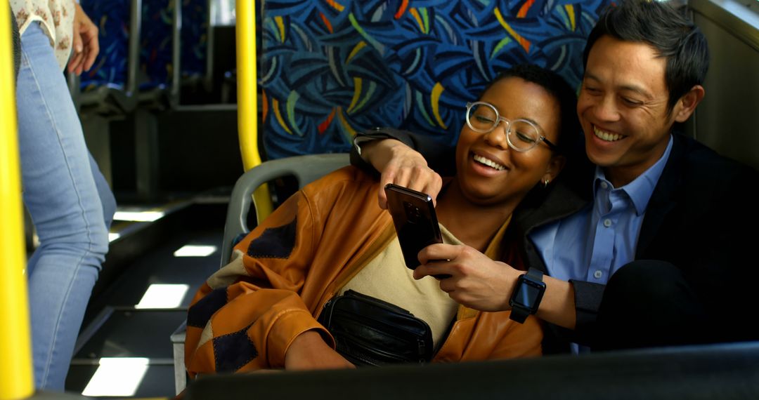 Happy diverse couple sitting in city bus embracing and using smartphone - Free Images, Stock Photos and Pictures on Pikwizard.com