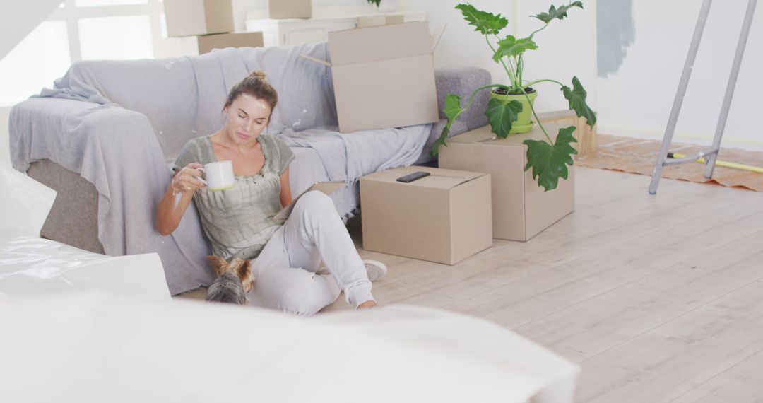 Woman Relaxing with Coffee Sitting Among Moving Boxes and Unpacked Items - Free Images, Stock Photos and Pictures on Pikwizard.com