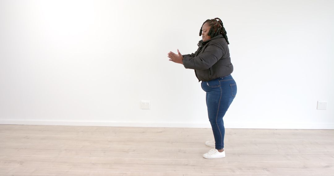 Determined Woman Practicing Squats Alone in Minimal Gym Space