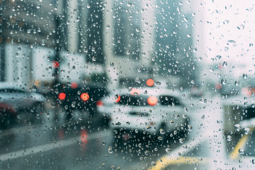 Rain Soaked Urban Window with Blurry Traffic Lights in Background