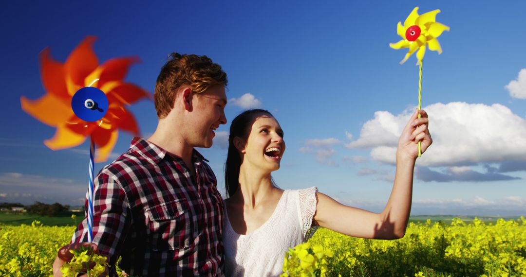 Smiling Couple Enjoying a Sunny Day in Countryside Holding Pinwheels - Free Images, Stock Photos and Pictures on Pikwizard.com