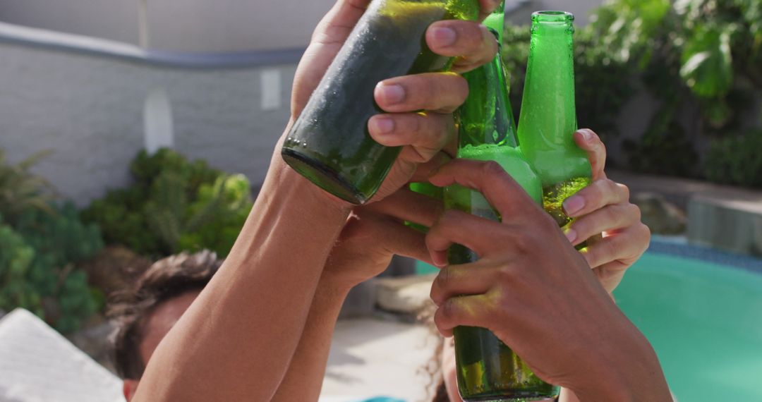 Friends Celebrating with Beer Bottles at Poolside Party