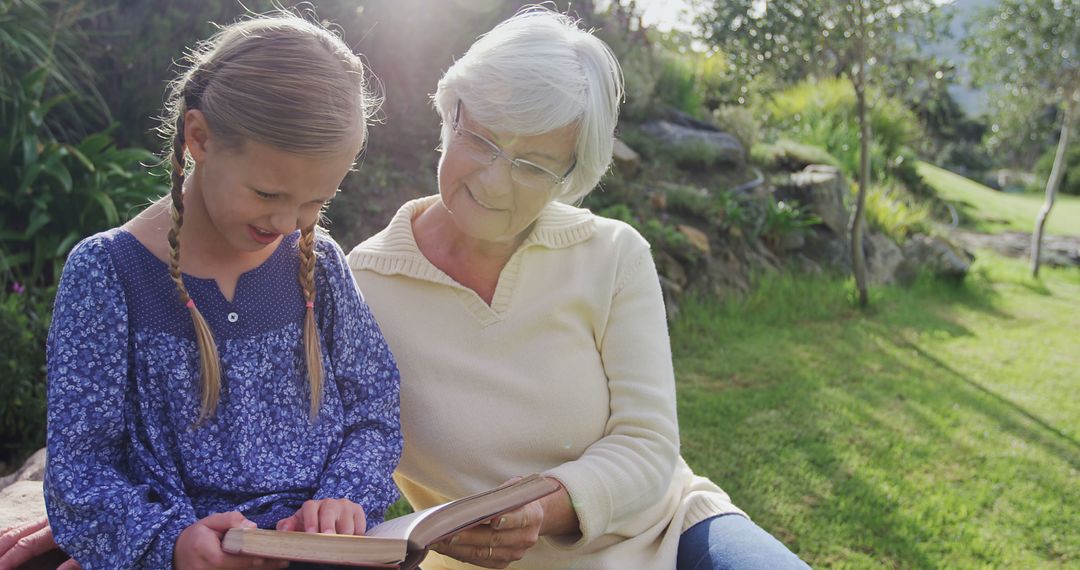 Grandmother Reading Book with Granddaughter in Park - Free Images, Stock Photos and Pictures on Pikwizard.com