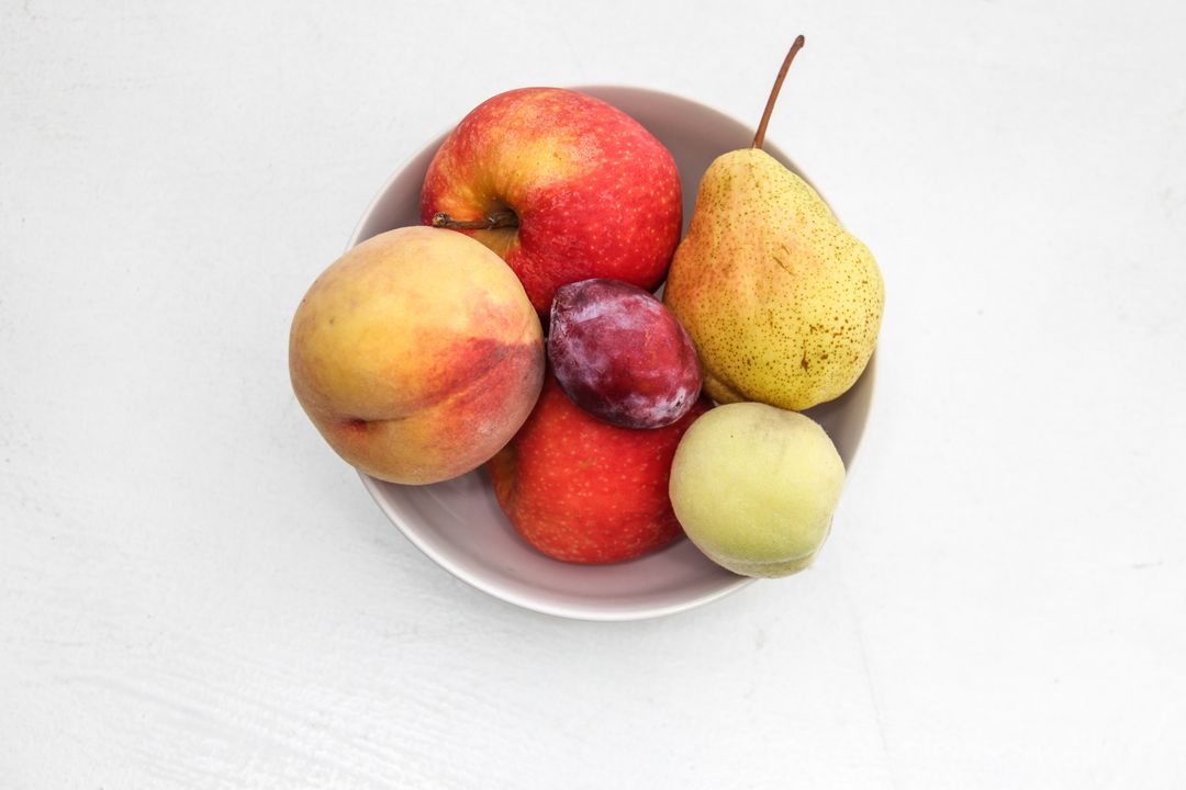 Top-Down Bowl of Mixed Summer Fruit on White Background for Healthy Eating