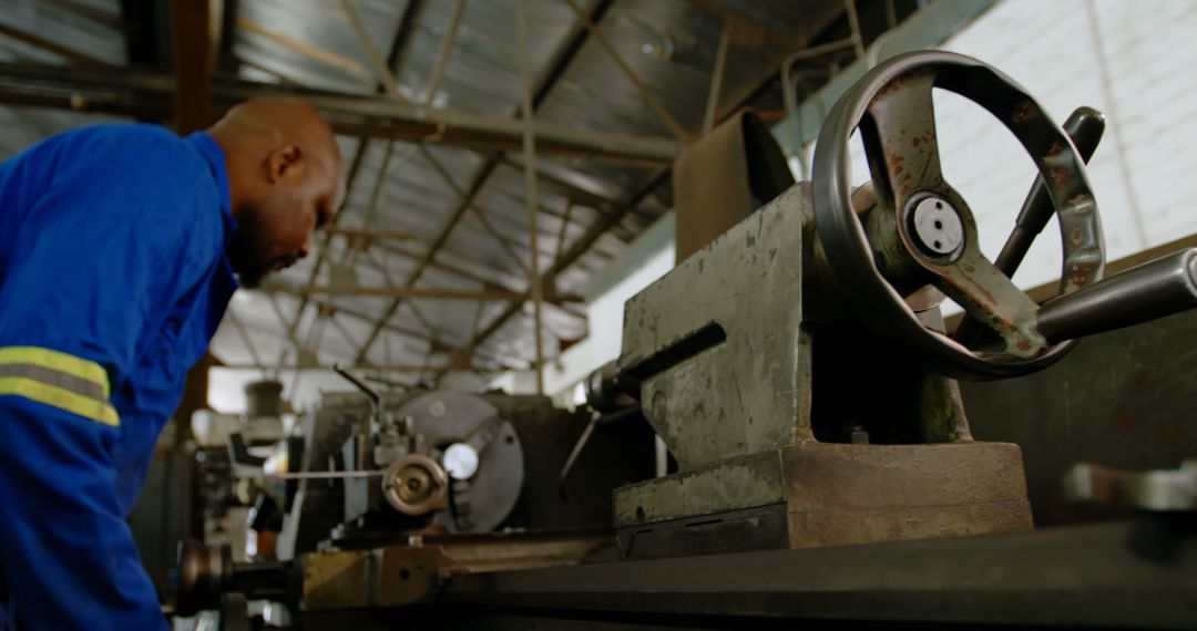 Male worker operating industrial lathe machine in warehouse - Free Images, Stock Photos and Pictures on Pikwizard.com