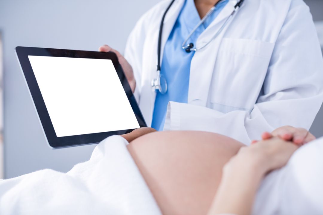 Doctor showing ultrasound scan on to pregnant woman on digital tablet - Free Images, Stock Photos and Pictures on Pikwizard.com