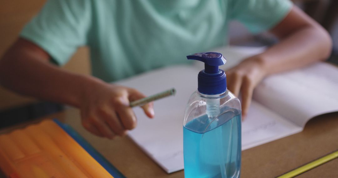 Student Writing During Class with Hand Sanitizer on Desk - Free Images, Stock Photos and Pictures on Pikwizard.com