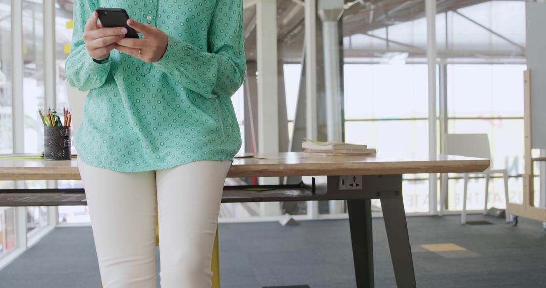 Woman in modern office wearing mint green blouse using smartphone - Free Images, Stock Photos and Pictures on Pikwizard.com