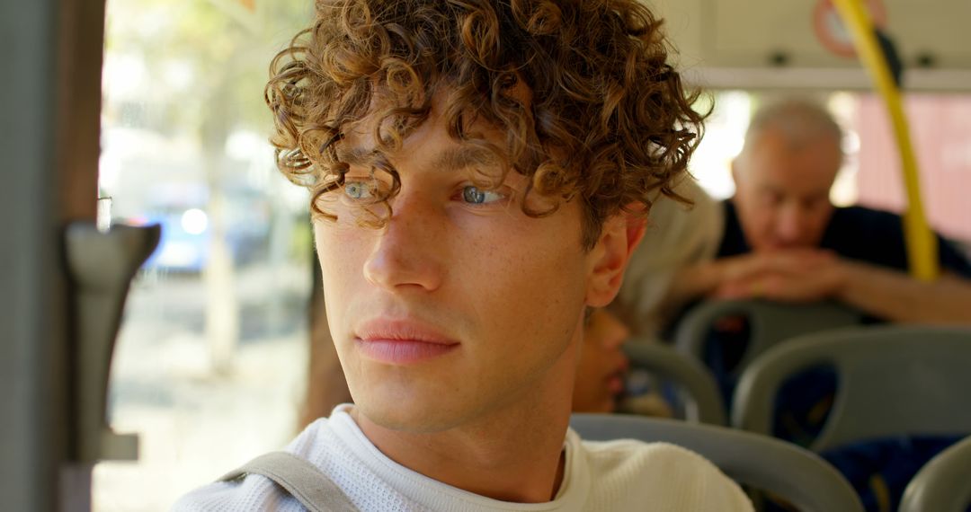 Thoughtful Man with Curls Gazing Out City Bus Window - Free Images, Stock Photos and Pictures on Pikwizard.com