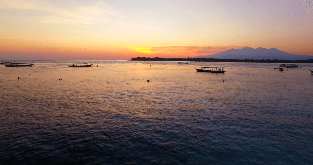 Transparent Sunset Over Serene Sea with Boats Silhouetted