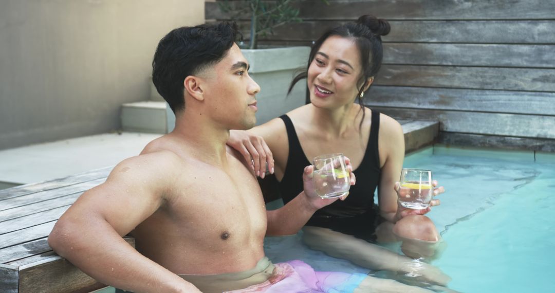 Couple relaxing in private plunge pool holding lemon drinks, intimate poolside moment