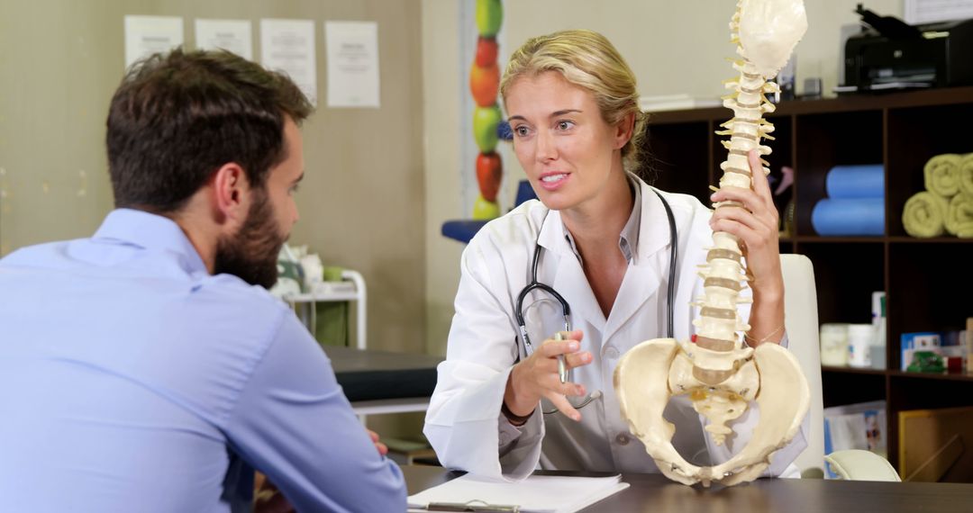 Doctor Discussing Spine Health with Patient Using Anatomical Model - Free Images, Stock Photos and Pictures on Pikwizard.com