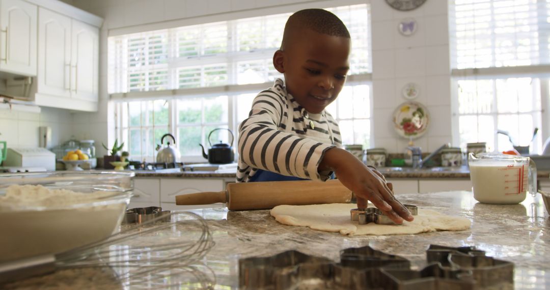 Young African-American boy baking with cookie cutters in sunny kitchen - Free Images, Stock Photos and Pictures on Pikwizard.com