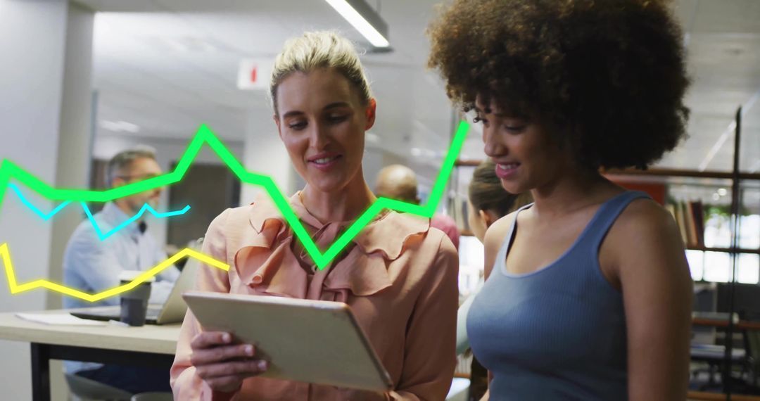 Colleagues reviewing tablet with colorful data charts in modern open office workspace