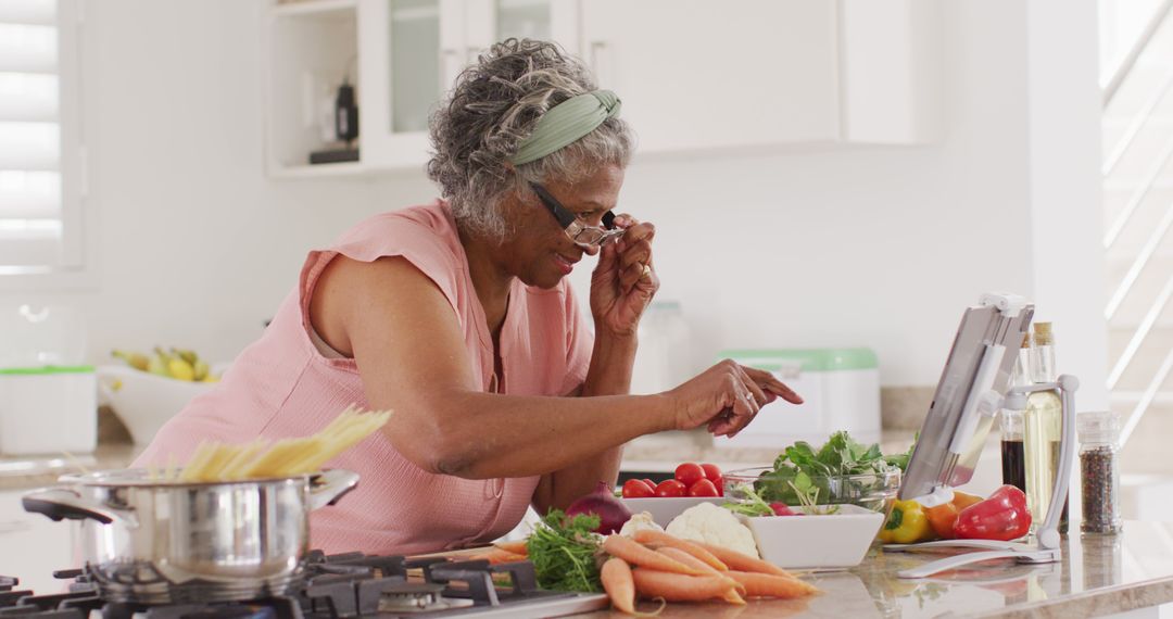 Senior African American Woman Cooking in Modern Kitchen, Looking at Tablet - Free Images, Stock Photos and Pictures on Pikwizard.com