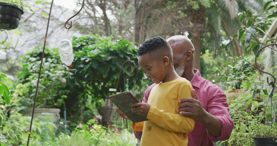 Senior Man and Grandson Using Tablet in Lush Garden - Free Images, Stock Photos and Pictures on Pikwizard.com