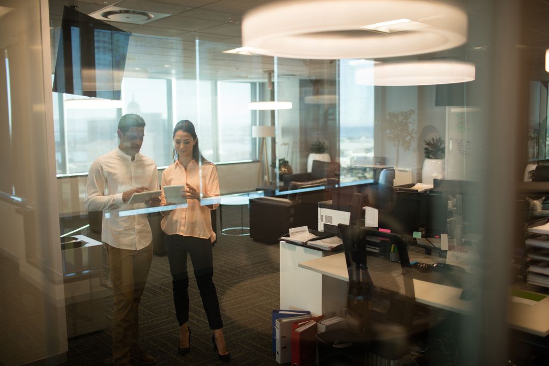 Office Colleagues Collaborating on Digital Tablet Behind Glass