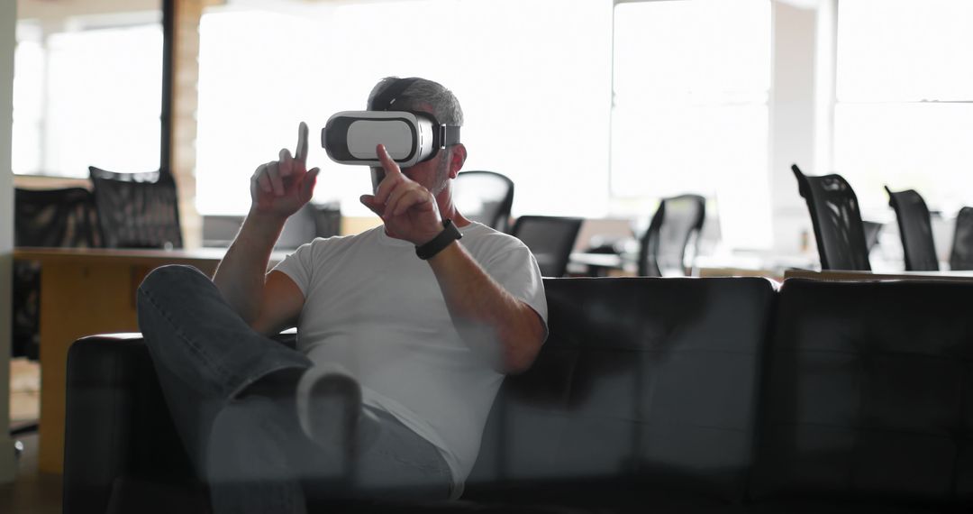 Man Experiencing Virtual Reality While Sitting on Couch in Office - Free Images, Stock Photos and Pictures on Pikwizard.com