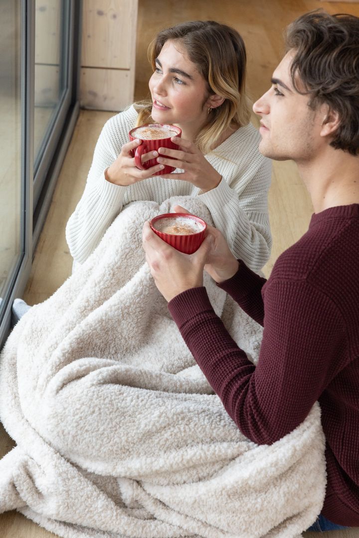 Cozy Couple Relaxing with Hot Drinks by Large Window