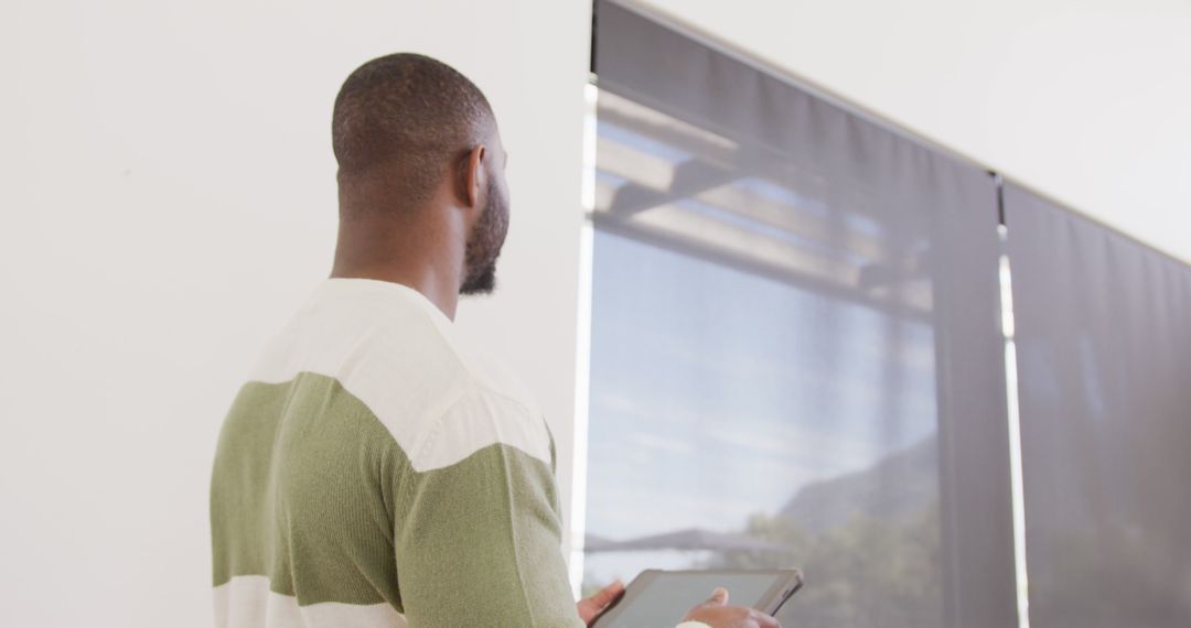 Man Standing by Window with Tablet in Modern Office - Free Images, Stock Photos and Pictures on Pikwizard.com