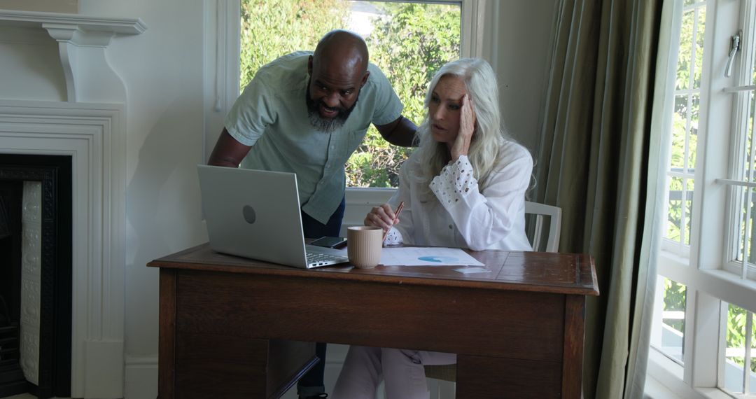 Elderly Couple Discussing Finances at Home with Laptop