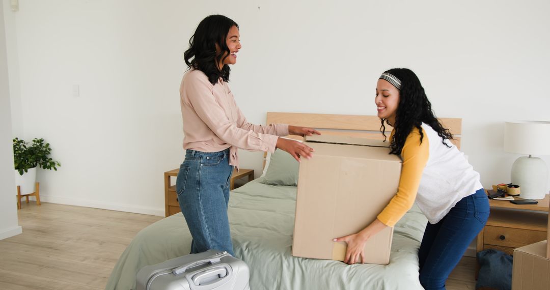 Women Smiling While Unpacking Boxes in Bedroom