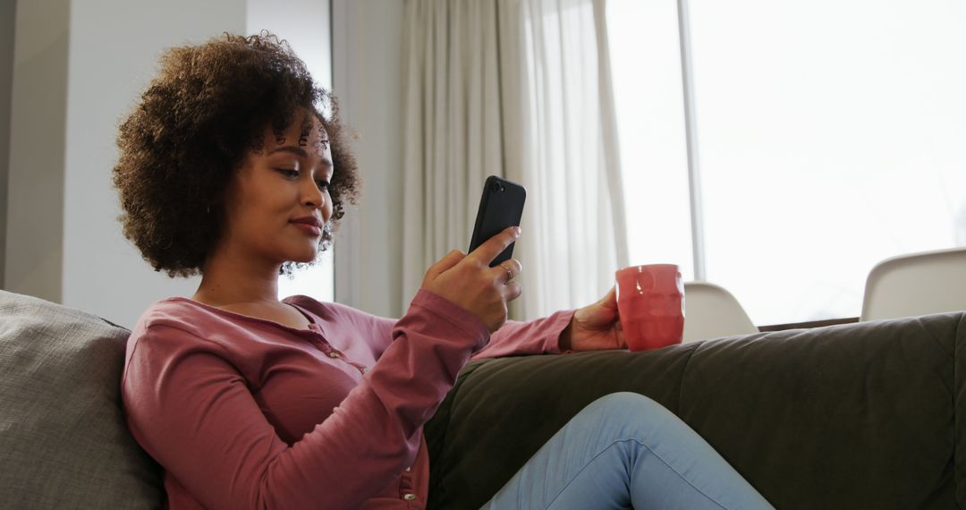 African American Woman Relaxing on Couch with Smartphone and Coffee Mug - Free Images, Stock Photos and Pictures on Pikwizard.com