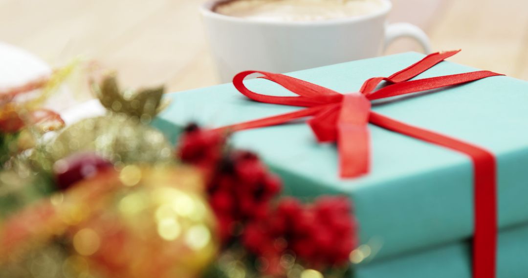 Close-Up of Blue Christmas Gift Box with Red Ribbon Next to Coffee Cup - Free Images, Stock Photos and Pictures on Pikwizard.com