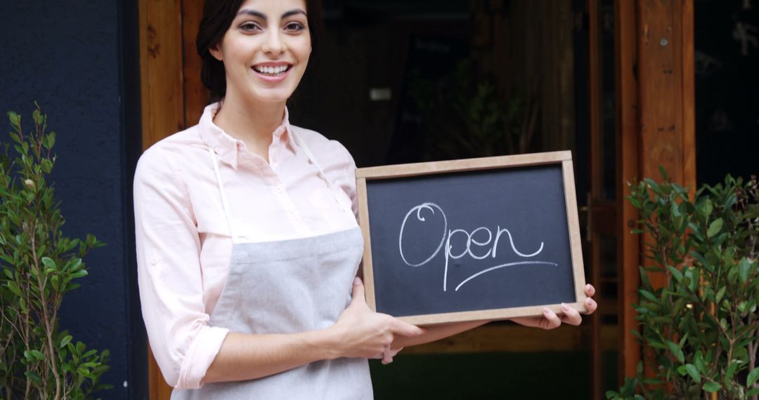 Smiling Female Shop Owner Holding Open Sign Board at Entrance - Free Images, Stock Photos and Pictures on Pikwizard.com