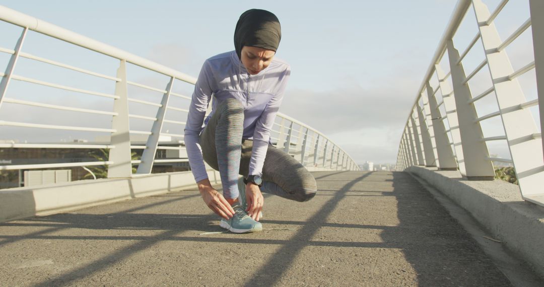 Muslim Woman Tying Running Shoes on Sport Footbridge - Free Images, Stock Photos and Pictures on Pikwizard.com