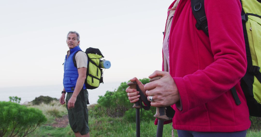 Senior Couple Hiking with Backpacks on Grass Field