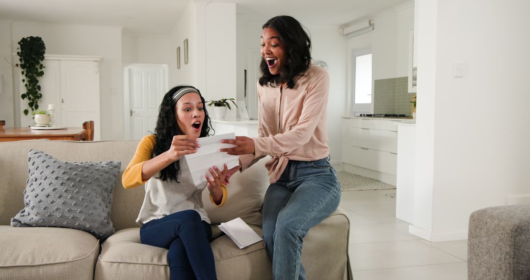 Enthusiastic Women Celebrating Success on Sofa at Home